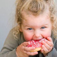 little girl eating jelly-glazed donut with sprinkles - junk food stock pictures, royalty-free photos & images