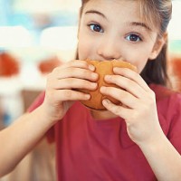 little girl enjoying a burger. - junk food stock pictures, royalty-free photos & images