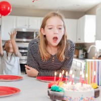 little girl prepares to blow out birthday candles on cake during party at home in kitchen - garden decoration stock pictures, royalty-free photos & images