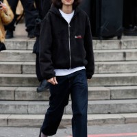 Loli Bahia wears black denim Stüssy jacket, white t-shirt, dark blue jeans, black loafaers, outside Sacai, during the Menswear Fall Winter 2025/2026...