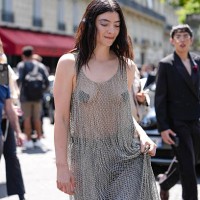 Lorde wears silver sheer mesh Balenciaga maxi dress, light blue baggy denim jean pants, shiny black pointed toe heels leather shoes, a silver ring,...