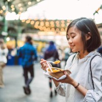 lovely cheerful girl enjoying a bowl of freshly made paella at food stall while exploring in city - junk food stock pictures, royalty-free photos & images