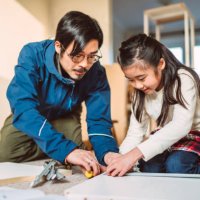 lovely cheerful girl helping her dad to assemble furniture in their new home - home decoration stockfoto's en -beelden