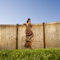 low angle view of a woman peeking over a wooden fence - garden decoration photos et images de collection