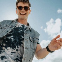low angle view of happy young man with tattooed arm dancing under cloudy sky - fashion stock pictures, royalty-free photos & images