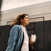 low angle view of young woman holding disposable cup while walking by tram - junk food stock pictures, royalty-free photos & images