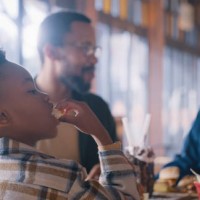 lunch, eating and boy with parents in restaurant with food, conversation or hungry kid at table. black family, mother and father with child in cafe for burger, drinks and bonding on weekend in africa - junk food stock picture