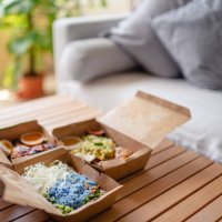 malaysian food nasi kerabu, nasi ulam and ayam percik in recycled paper container with sauce on coffee table beside sofa in living room - junk food stock pictures, royalty-free photos & images