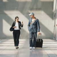 male and female business colleagues talking while walking at airport - fashion photos et images de collection