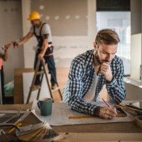 male architect drawing improvements on housing plan at construction site. - home decoration stock pictures, royalty-free photos & images