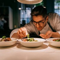 male chef plating food in plate while working in commercial kitchen - food stock pictures, royalty-free photos & images