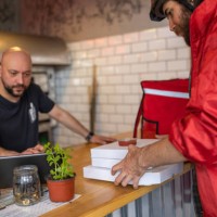 male delivery person, picking up the food at the fast food restaurant for delivery - junk food stock pictures, royalty-free photos & images