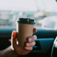 male hand with craft coffee in the car. disposable dishes, coffee on the road while driving. - junk food stock pictures, royalty-free photos & images