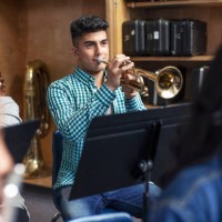 male middle eastern ethnicity student practicing trumpet with friends in school orchestra band - concert stock pictures, royalty-free photos & images