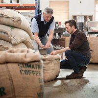 male owner of a coffee roasting business talking with worker - coffee stockfoto's en -beelden