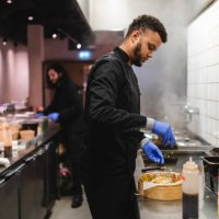 male waiter sprinkling scallion on dumplings in bowl over kitchen counter at restaurant - junk food stock pictures, royalty-free photos & images