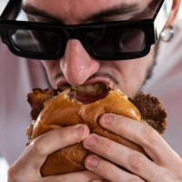 Man bites a bacon cheeseburger at Meat Crew fast food restaurant on May 28, 2023 in Milan, Italy. On occasion of the World Burger Day, celebrated on...