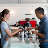 man buying a cup of coffee to go and making a contactless payment at a coffee shop - junk food stock pictures, royalty-free photos & images