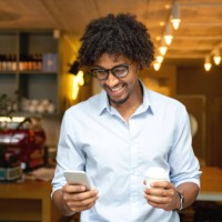 man buying a cup of coffee to go at a cafe while texting - junk food stock pictures, royalty-free photos & images