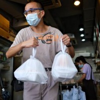 Man carries bags containing takeaway meals in Hong Kong on July 29 after new social distancing measures came into effect which include restaurants...