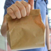 man carrying brown paper bag, lunch bag - junk food stock pictures, royalty-free photos & images