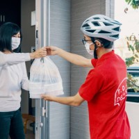 man delivering food to a mature woman while practicing social distancing measures - junk food stock pictures, royalty-free photos & images