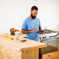 man doing diy in kitchen with tablet computer - home decoration stockfoto's en -beelden