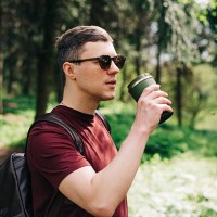man drinking from a travel mug while exploring a forest trail - junk food stock pictures, royalty-free photos & images
