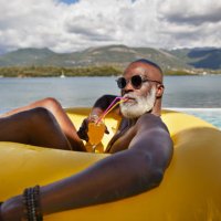 man drinking juice in inflatable ring - travel stock pictures, royalty-free photos & images