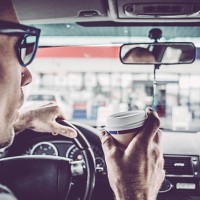man driving his car and drinking take away coffee - junk food stock pictures, royalty-free photos & images
