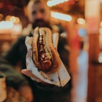 man eating a sausage hot dog and enjoying a christmas market - food stock pictures, royalty-free photos & images