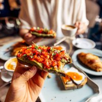 man eating avocado toast with tomato at the cafe, personal perspective view - food stock pictures, royalty-free photos & images