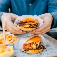 man eating cheeseburger and cheese fries at fast food joint - junk food stock pictures, royalty-free photos & images