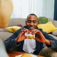 man eating chicken burrito, wide shot pov. - junk food stock pictures, royalty-free photos & images