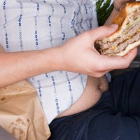 man eating fast food in his car - junk food stockfoto's en -beelden