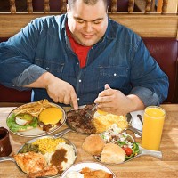man eating from multiple plates of food in restaurant - junk food stock pictures, royalty-free photos & images