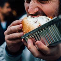 man eating hot dog on the streets - junk food stock pictures, royalty-free photos & images