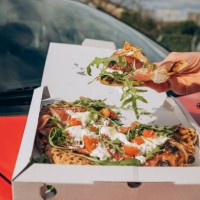 man eating pizza on the hood of a red car in a parking lot male hands - junk food stock pictures, royalty-free photos & images
