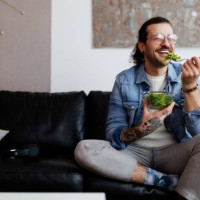 man eating salad and drinking water at home - food stockfoto's en -beelden