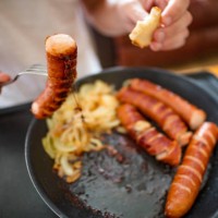 man eating sausages, close-up for breakfast on hot electric hob - junk food stock pictures, royalty-free photos & images