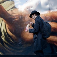 Man eats while walking past a large detail reproduction of Caravaggio's 'The Supper of Emmaus' outside the National Gallery that is in 2023,...