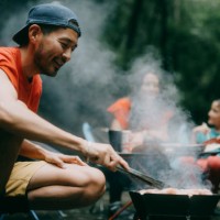 man enjoying bbq with family in nature - food stock pictures, royalty-free photos & images
