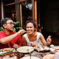 man feeding snack to woman at dining table - food stock pictures, royalty-free photos & images