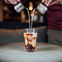 man gieten melk in iced coffee - coffee stockfoto's en -beelden