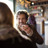 man having coffee while looking at woman in cafe - coffee stockfoto's en -beelden