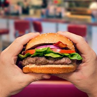 man holding a hamburger in a diner - junk food stock pictures, royalty-free photos & images