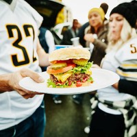 man holding burger on plate at tailgating party - food stock pictures, royalty-free photos & images