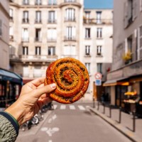 man holding fresh french pastry pain aux raisins on a street in paris, france - food stock pictures, royalty-free photos & images