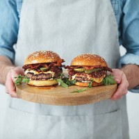 man holding homemade angus beef burgers with bacon whisky jam - junk food stockfoto's en -beelden