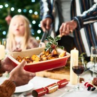 man holding serving dish with roast potatoes and a sprig of holly for christmas dinner - food stock pictures, royalty-free photos & images